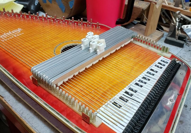 An autoharp with several buttons attached to bars. There are thick white pads on the underside of each bar.